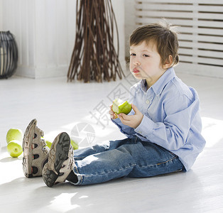 可爱的小可爱男孩在家里吃绿苹果图片
