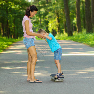 母亲和儿子在滑板上年轻母亲教她的图片