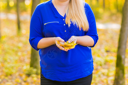 黄叶在秋天公园散步的年轻女孩图片