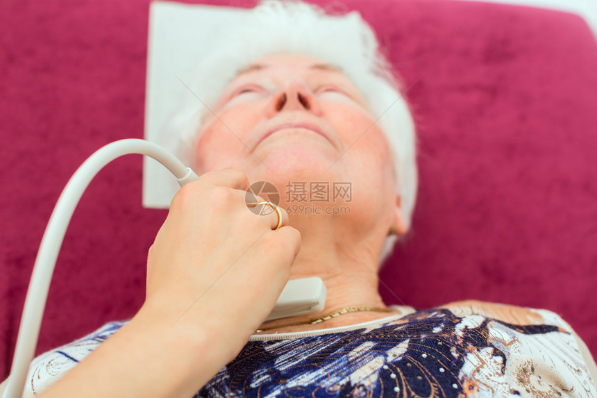女医生对高级病人使用外科超声波装置的甲状腺进图片