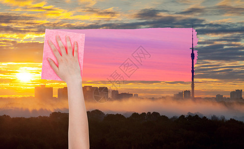 天气概念手用粉红色布从图像中删除城市上空的黄色日出天空图片
