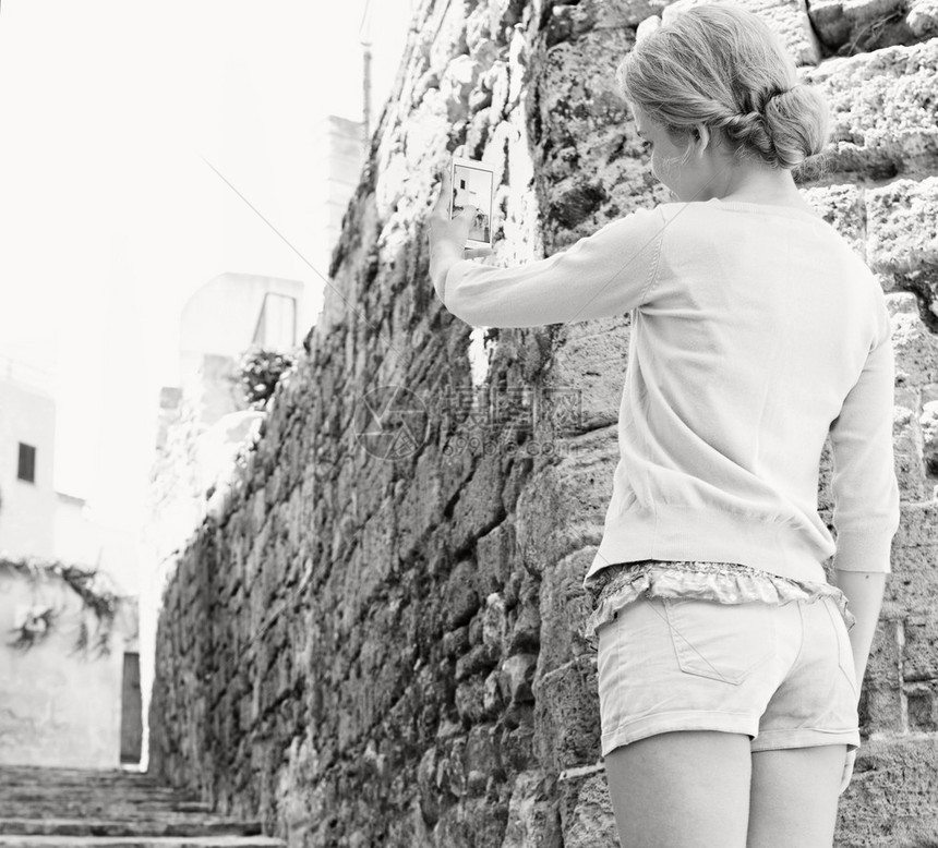 一位年轻迷人的旅游女站在风景如画的狭窄石街上图片