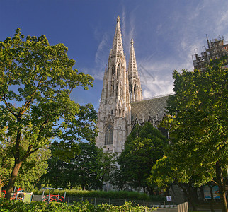 老教堂塔的全景与花园的绿树的缩短图片