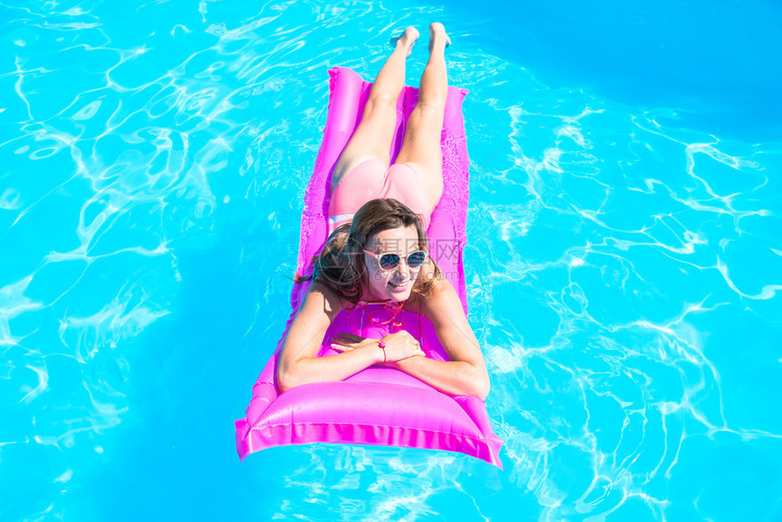 女孩漂浮在游泳池的充气床垫上图片
