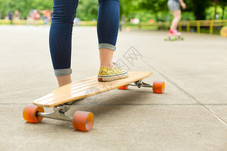 穿着蓝色牛仔裤和运动鞋的少女在滑板公园玩长板游戏图片