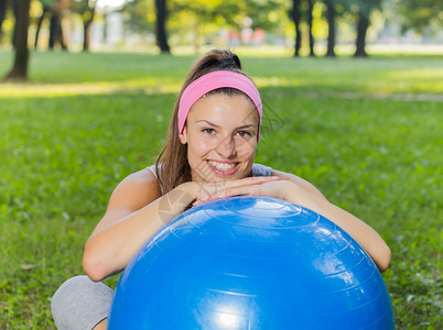 搁在普拉提球上健身健康微笑年轻女人图片