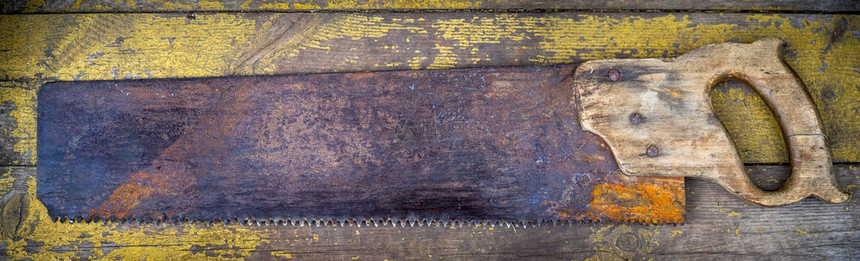 在木制背景上看到老旧的生锈工具木匠锯图片