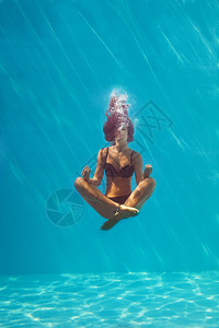 身穿黑色比基尼的年轻黑比基尼女子在瑜伽姿势下潜入水族馆全身中图片