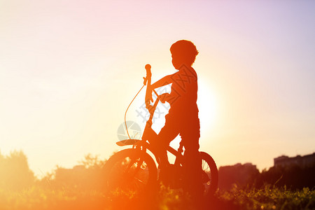 日落时骑自行车的小男孩活图片