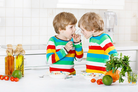 两个有趣的双胞胎男孩在室内厨房里玩得开心图片