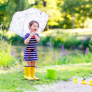 在夏日公园玩黄色橡皮鸭的黄雨靴小可爱女孩图片