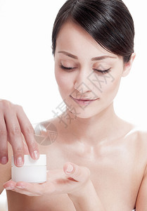 美丽的女人在脸上施了化妆品奶油治疗皮图片