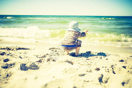 小孩在夏日天气好时在海边玩耍照片带有古背景图片