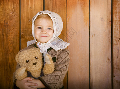 微笑的小女孩的肖像用玩具熊织着古老图片