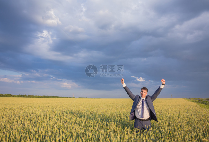 快乐的商人站在田野上面向天空图片