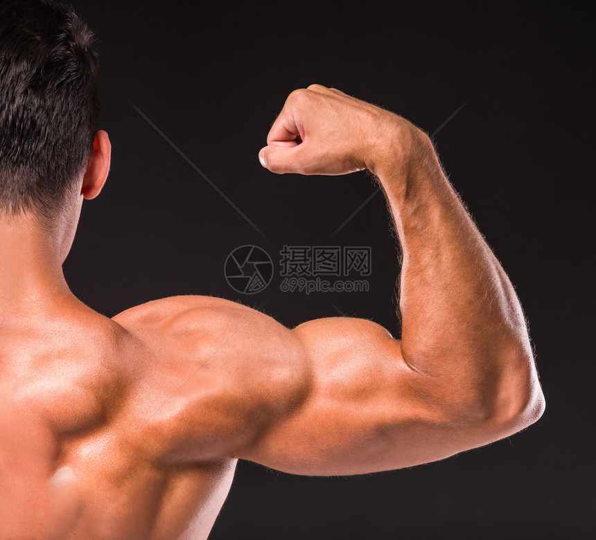 体育运动员的后视线显示背后的肌肉手在黑暗背景上图片