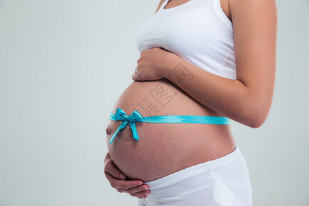 一位怀着礼物丝带的孕妇在腹部与白种背景隔图片