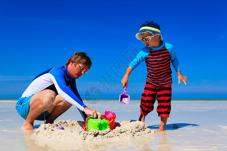 父亲和儿子修建沙城堡夏季海滩上图片