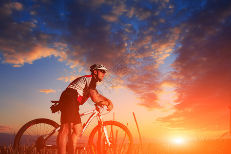 日出背景山上的山地自行车骑手背景图片
