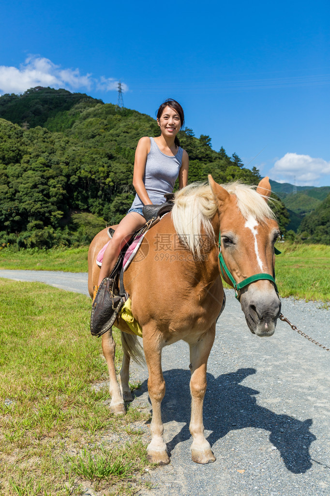 在农村骑马的亚洲年轻女子图片