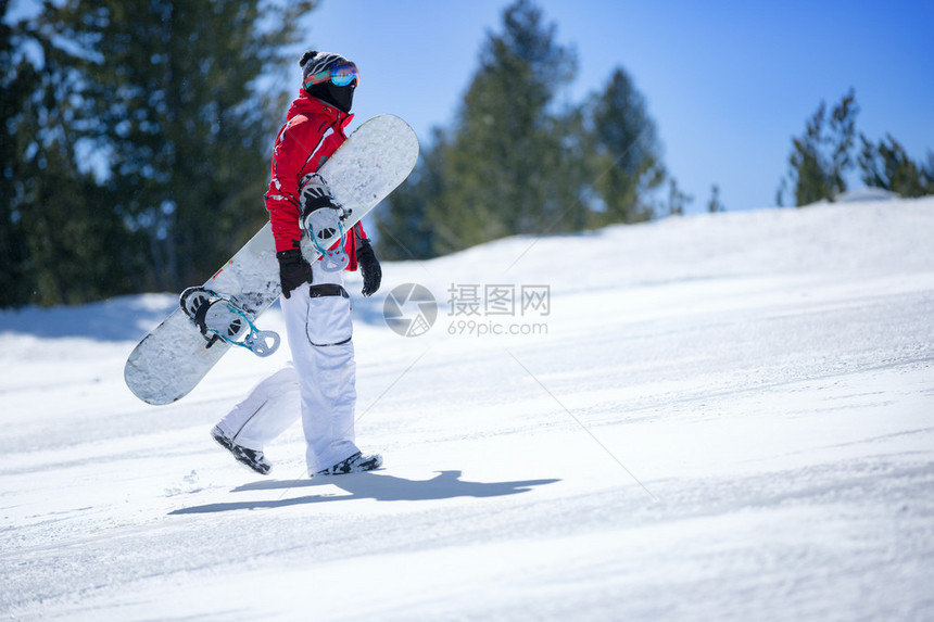 滑雪板手拿着滑雪板爬上斜坡图片
