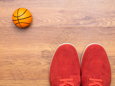 木地板上的一双红色运动鞋和篮球背景图片