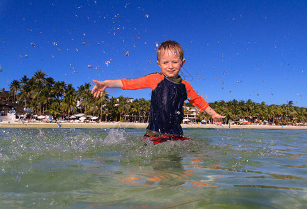 在热带海滩上玩水的小男孩图片