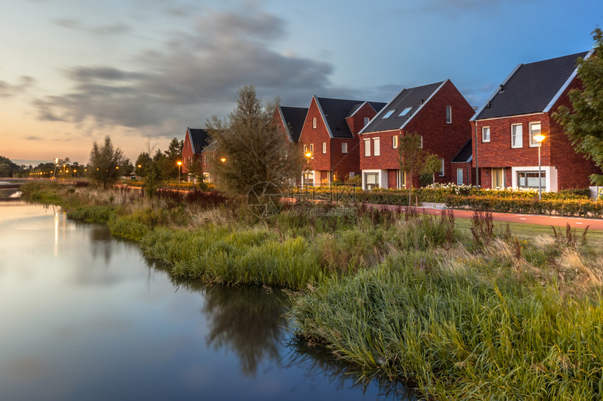 在荷兰Veenendaal市与生态友好河岸的现代生态中产阶级家庭住宅相邻的街道上图片
