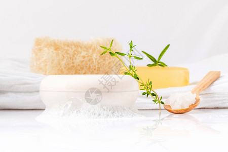 丝瓜油馓子白色浴巾上的草药香皂棒背景