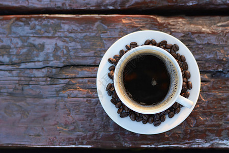 旧木桌上杯子里的黑咖啡和咖啡豆顶视图图片