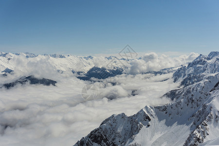 俄罗斯索契的克拉斯纳亚波拉那索奇等地云层上空的寒冬雪山和蓝图片