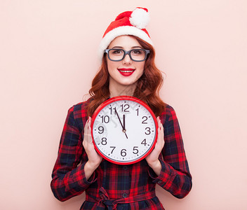 一个穿着圣诞老人帽子时钟贴着粉红色背景的黑图片