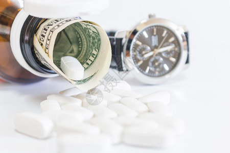 白色药丸和白色背景上的钱图片