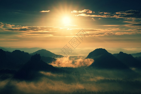 重度薄雾黎明在一个奇妙的丘陵萨克森瑞士公园的薄雾日出山峰从浓密的图片