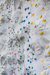 黄色蓝和绿色手和脚握在攀岩墙上背景图片