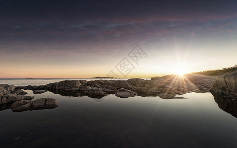 太阳升起在海平面的岩石海岸线上平静和图片