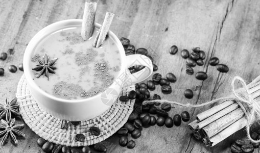 咖啡杯上含咖啡豆和肉桂棍的咖啡图片