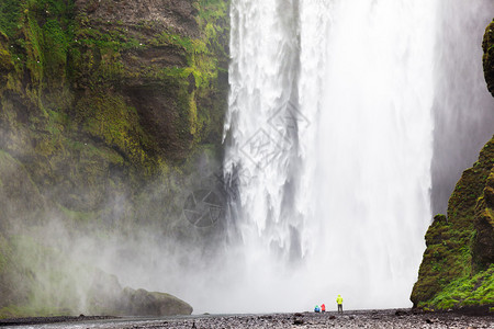 游客在位于冰岛南部的斯科加瀑布前图片