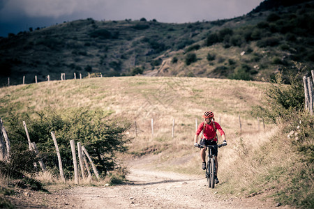 山地车手骑在秋季山区的自行车单轨小道上在乡村公路或单轨上骑山地车的男子骑手美丽的励志景观中的运动健背景图片