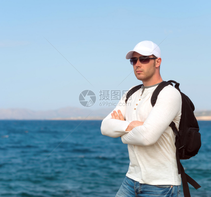 背着包站在海边的男游客图片