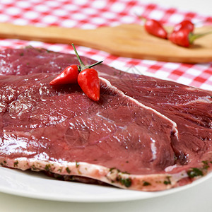 关闭厨房桌上一个盘子上一些生熟的牛肉填料图片