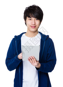 蓝色毛衣的亚洲年轻人与平板电脑图片