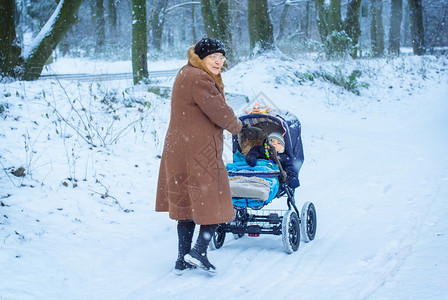 曾祖母在冬天下雪时与婴儿一起在小儿园散步图片