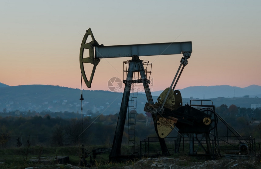 夕阳天空下的石油和天然气井图片