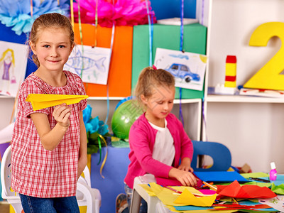 一群孩子在幼儿园室内制作折纸飞机图片