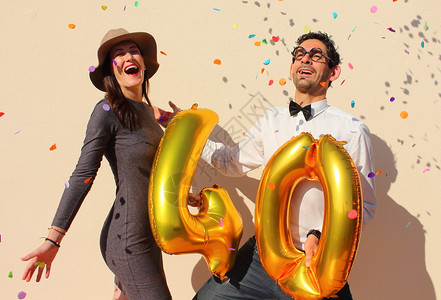 开朗的夫妇庆祝四十岁生日与的大气球和多彩小纸片在空气中图片