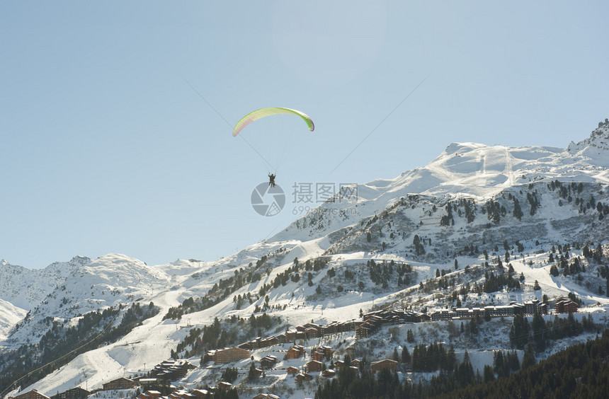 滑翔伞在高山脉的雪上飞过图片