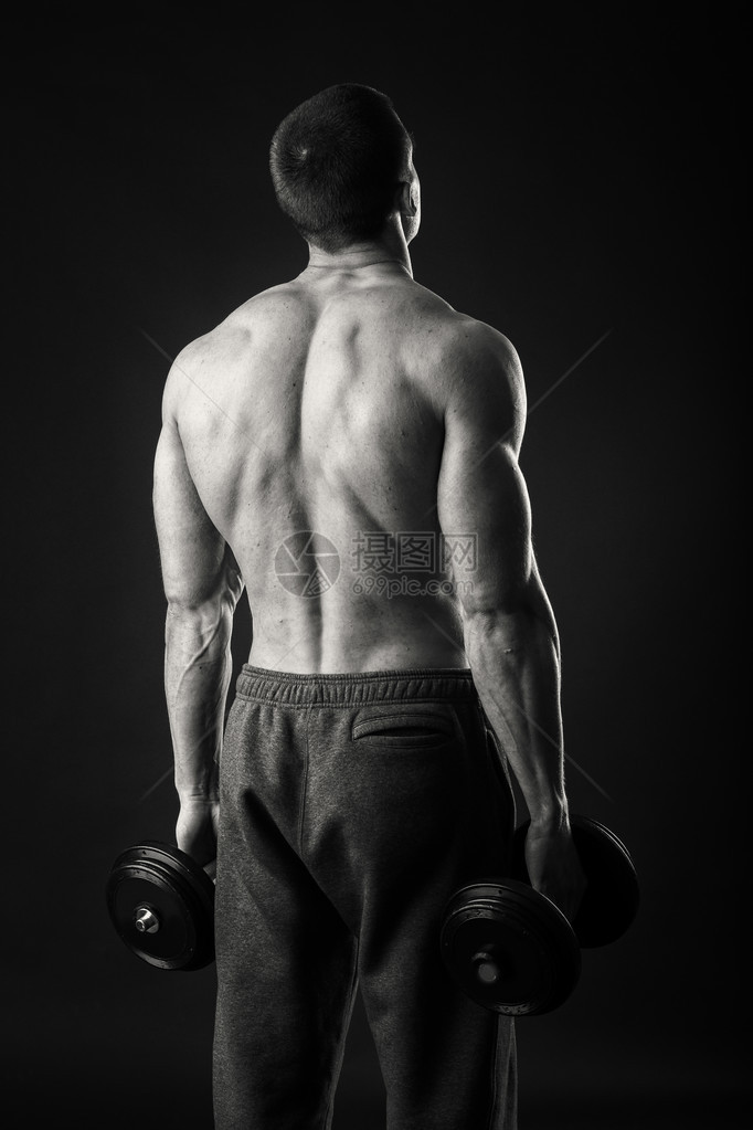 肌肉发达的男人在深色背景上用哑铃锻炼运动员在负荷下展示他的肌肉在你的身体上工作体育杂志海报图片