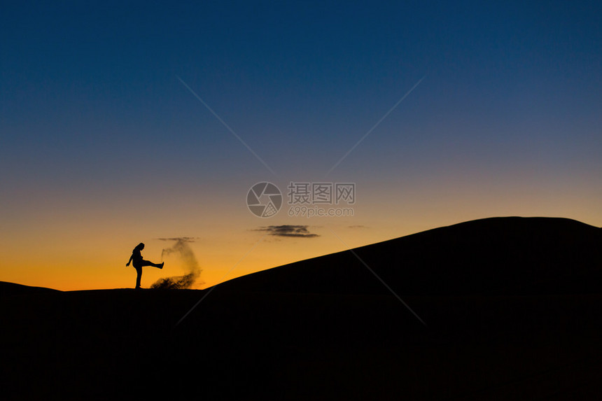 日落时在沙漠中玩沙子的人图片