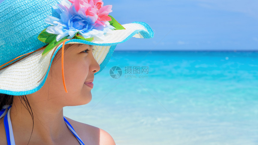 穿着蓝色泳装的女孩在沙滩上快乐地坐着图片